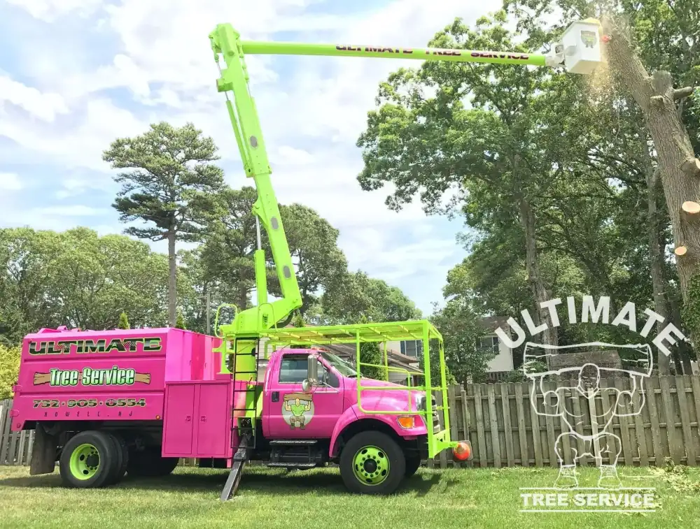 Ultimate Tree Service's pink and lime bucket truck mid-lift on a job
